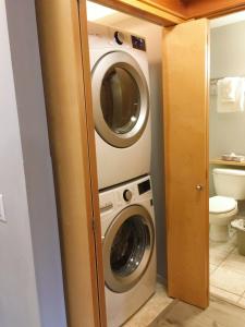 a washer and dryer in a small bathroom at Windtower Lodge FullKitchen-Kingbed Suite-MntView-UGParking-Walk2DT in Canmore