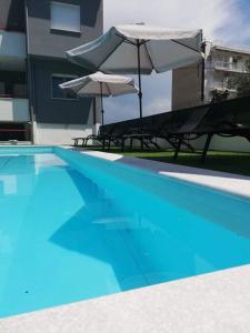 two chairs and umbrellas sitting next to a swimming pool at MGE Luxury house with pool in Iraklitsa