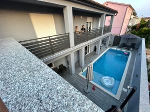 two people standing on the balcony of a house with a swimming pool at Villa Maleo in Medulin