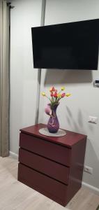 a vase with flowers on top of a dresser at D&Y Studio- Piatra Neamț in Piatra Neamţ