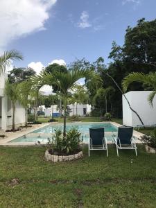 2 chaises assises en face d'une piscine dans l'établissement Corte de Los Angeles, à Puerto Morelos