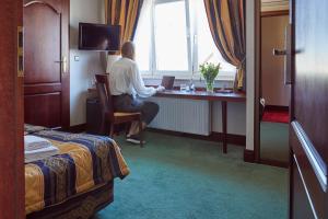 Una donna seduta alla scrivania in una stanza d'albergo di Hotel Villa Eva a Danzica