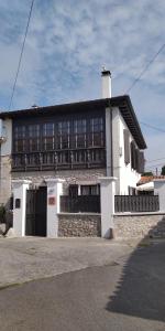 un grand bâtiment blanc avec un toit noir dans l'établissement Casa de Aldea la Galeria habitación en casa particular, à Poo de Llanes