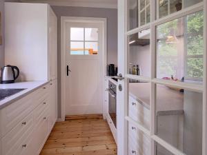 a kitchen with white cabinets and a hallway with wood floors at 6 person holiday home in Gilleleje in Gilleleje