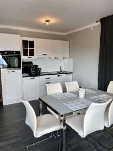 a kitchen with a dining table and white chairs at Apartments Prestige in Petrcane