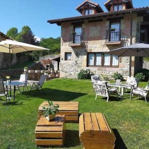 une maison avec des tables et des chaises dans la cour dans l'établissement La Riguera de Ginio, à Ucieda de Arriba