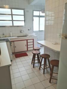 a kitchen with two stools and a counter in it at Apartamento Das Conchas Praia das Pitangueiras in Guarujá