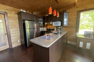 a kitchen with a refrigerator and a counter top at Joy's Chalet - Hottub, Lake, & Cottage in Val-des-Bois
