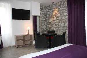 Habitación de hotel con mesa y pared de piedra. en Hôtel Terranostra en Tarascon-sur-Ariège