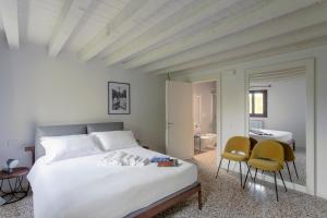 Un dormitorio con una cama grande blanca y dos sillas en Palazzo Venere Apartments, en Venecia 104 fotos más