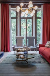sala de estar con sofá rojo y lámpara de araña en Palazzo Venere Apartments, en Venecia