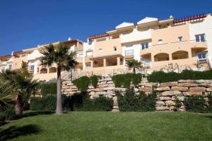 a large building with a palm tree and a stone wall at Tarifa Beach Rentals Almenara in Tarifa