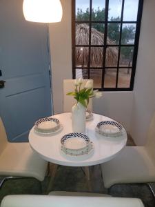una mesa blanca con platos y un jarrón con flores. en Portón Náutica, en San Bernardo del Viento