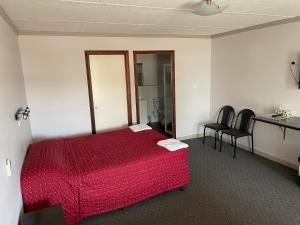 a bedroom with a red bed and two chairs at Paringa Hotel Motel in Renmark