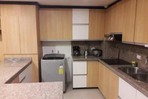 a small kitchen with a refrigerator and a sink at Hermoso apartamento en condominio La Victoria in Cuenca