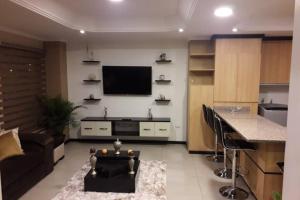 a living room with a couch and a tv on a wall at Hermoso apartamento en condominio La Victoria in Cuenca
