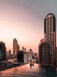 two people standing on the edge of a building with a city at Eastin Grand Hotel Sathorn in Bangkok