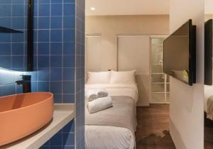 a bathroom with a tub and a bed and a tv at The Great Madras by Hotel Calmo in Singapore