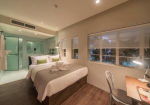 a bedroom with a large bed with a desk and a window at The Great Madras by Hotel Calmo in Singapore