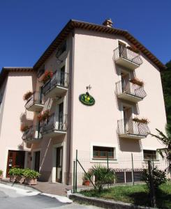 ein weißes Gebäude mit Balkonen und Pflanzen darauf in der Unterkunft Albergo La Casa Nel Bosco in Col Sant'Angelo