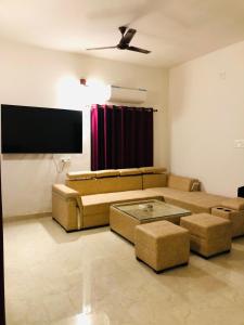 ein Wohnzimmer mit einem Sofa und einem Flachbild-TV in der Unterkunft Tattva 2 in Varanasi