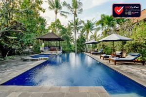 una piscina en un complejo con sillas y sombrillas en Alam Shanti Ubud, en Ubud