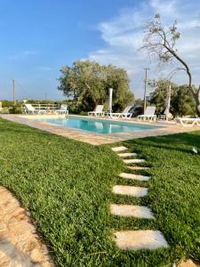 a stepping stone path in the grass next to a swimming pool at Trullo Nadia Ostuni in Ostuni