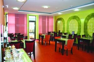 ein Restaurant mit Tischen und Stühlen sowie rosa und grün gestrichenen Wänden in der Unterkunft Garni Hotel Cosmopolitan in Senec