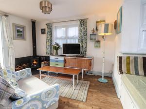a living room with a couch and a tv at Wood Glen Cottage in Dallington