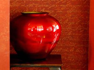 a red vase sitting on a table next to a wall at Delphi Art Hotel by Prima Hotels in Athens