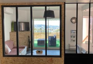- un salon avec une grande fenêtre en verre et un canapé dans l'établissement Gîte « la sakalava » vue panoramique faron, à Toulon
