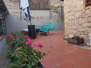un patio con 2 sillas, sombrilla y flores en Melvilla Studio, en Johannesburgo
