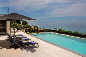 uma piscina com duas espreguiçadeiras e um guarda-sol em Mystique View Villas em Lourdhata