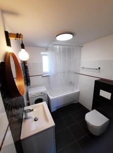 a bathroom with a tub and a toilet and a sink at Apartament na Cysterskim Szlaku in Starzyno