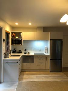 La cuisine est équipée de placards blancs et d'un réfrigérateur en acier inoxydable. dans l'établissement Cherrywood Cottage, à Akaroa