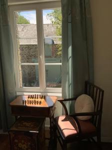 a chess board and a chair in front of a window at Les Voiles Vertes in Moidrey