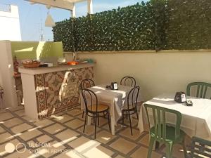 2 tafels en stoelen op een patio met een heg bij B&B L'Antica Dimora ...e dei mestieri in Otranto