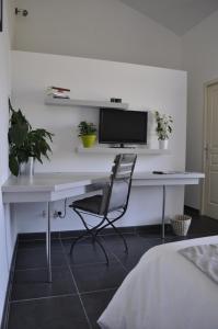 einen Schreibtisch mit einem Monitor und einem Stuhl in einem Schlafzimmer in der Unterkunft Le Mas de Plein Pagnier in Mazan