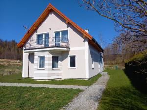 a white house with a balcony on a green field at Apartamenty EverySky - Dom Źródlana 11 in Kowary