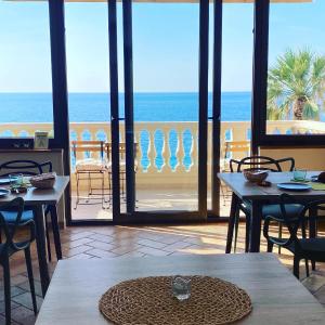 restauracja ze stołami i krzesłami oraz widokiem na ocean w obiekcie Le Camere di Rosanna w mieście Marina di Gioiosa Ionica