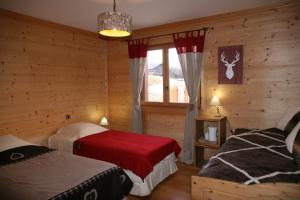 a bedroom with two beds in a log cabin at Les Marm'hôtes in La Côte-dʼAime