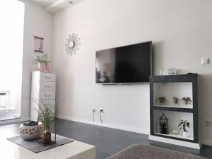 a white living room with a flat screen tv on the wall at Apartment Orchidee in Pula