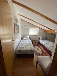 una piccola stanza con due letti e una sedia di Renic Apartments a Nin