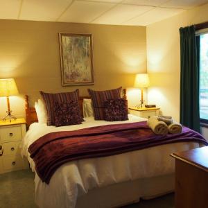 a bedroom with a large bed with two lamps at Forest Lodge Chalets in Bright