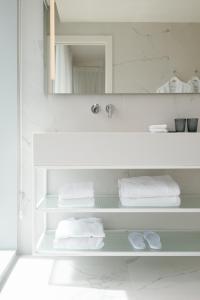 a bathroom with white towels and a mirror at Ink Hotel in Tel Aviv