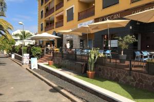un restaurante con sillas y sombrillas frente a un edificio en Casa Reinhart sehr schönes Apartment um Teneriffa zu erkunden, en Palm-mar