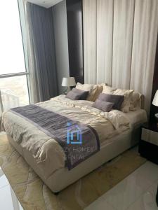 a large bed in a bedroom with a large window at Downtown Dubai, Damac Maison Upper Crest in Dubai