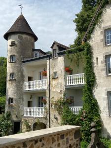 um edifício antigo com uma torre e flores em Gites Le Vieux Vinzelles em Volvic
