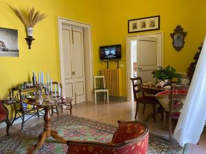 - un salon avec des murs jaunes, une table et des chaises dans l'établissement BACCHINGHAM, à Alessano