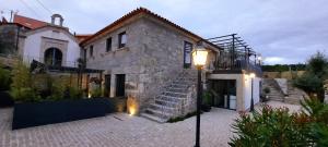 una casa de piedra con una escalera delante de ella en Lodges Minho en Ponte da Barca